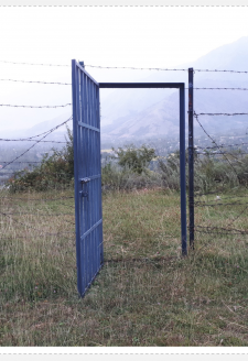 <strong>1. Barbed Gateway: </strong><br>
<br>
Policing (restricting and permitting) access to social spaces is one-way social mobility in Indian occupied Kashmir is regulated as a war zone. Here you see that a heavy metal door with barbed wires has been placed by the state to restrict access to a Buddhist monastery ruins (from approximately A.D. 78), on a mountain top in Kashmir. Looking beyond the barbed wires and gate, you see a glimpse of the Kashmir valley from this mountain top. <br>
<br>
This gate symbolically reflects the militarized regulation of this Himalayan mountain valley range, where human mobility is controlled by militarized state’s determination of what and/or who deserves safety, as well as security. It is evident that the restrictions in place at these ancient monastery ruins is in part to regulate access to space, thereby securitizing space, and restricting/regulating undesired human activity, such as preventing  the Bakarwal population of Kashmir from using it for grazing and rearing their sheep and mountain goat herds. <br>
<br>
The militarized securitization of Kashmiri land by the genocidal occupying, colonizing Indian state has been presented by the colonizer as its inherent ‘security’ need, namely, control of the border and the Kashmiri population. However, the human subjects constructed to be ‘Indian citizens’, the Kashmiri people, are regular targets of violence by Indian military forces without civil court or judicial oversight. Kashmiris live under normalized insecurities due to a violent militarized colonial state social order, where war measure laws such as the Jammu and Kashmir Public Safety Act 1978 (PSA), the 1990 Armed Forces (Jammu and Kashmir) Special Powers Act, and the Unlawful Activities (Prevention) Act (UAPA) serve to protect colonizing Indian military / paramilitary personnel domestically within India from committing what are war-crimes under international law. It is evident that ‘securing’ land is valued by the colonizing Indian regime, while Kashmiri lives are to be annihilated. <br>
<br>
What the militarized state cannot regulate is the movement of Kashmiri birds and other species. They defy borders, defy imposed limits on their freedoms. Kashmiri ‘insurgents’, ‘rebels’, non-human lives do not demand freedom, they are free, because they act free. This is the spirit of Kashmiri self-determination; it is beyond the containment capability of a colonizing power.